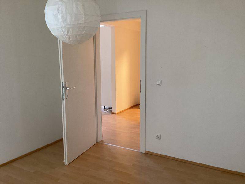 Heller Flur mit Laminatboden und einer offenen Tür, die in einen weiteren Raum führt.
