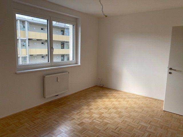 Geräumiges Schlafzimmer mit Parkettboden und Fenster, bereit für individuelle Einrichtung.
