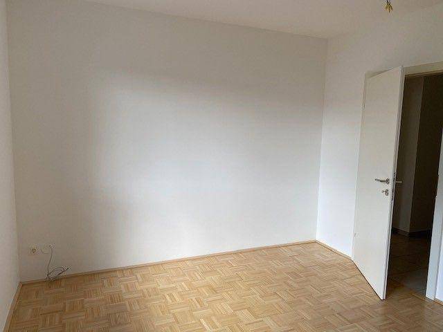 Leeres Zimmer mit hellem Parkettboden und weißen Wänden, bereit zur individuellen Gestaltung.