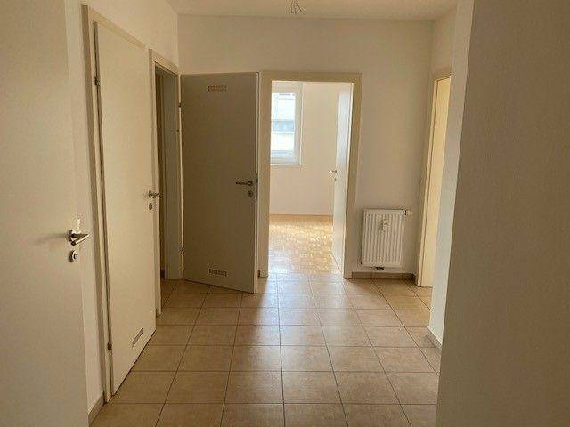 Heller Flur mit Fliesenboden und Zugang zu verschiedenen Zimmern der Wohnung.