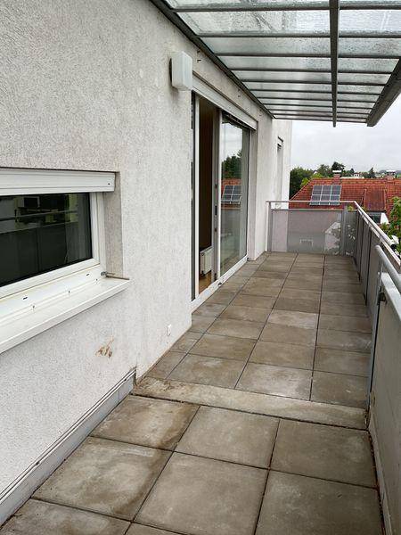 Langer Balkon mit Fliesenboden und Glasüberdachung, bietet Blick auf die Umgebung.
