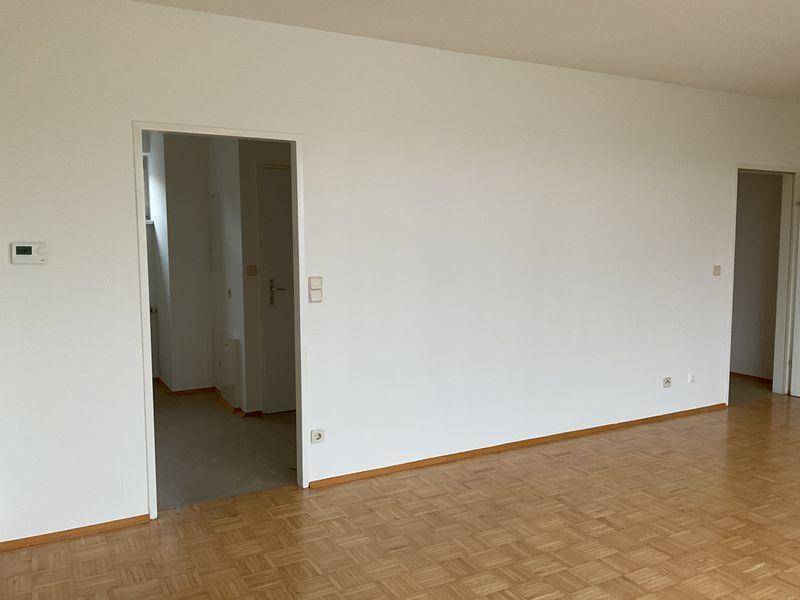 Geräumiges Wohnzimmer mit Parkettboden und weißen Wänden, bereit zur Einrichtung.
