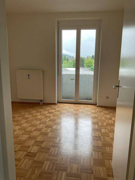 Schlafzimmer mit Parkettboden und Zugang zu einem Balkon oder einer Terrasse.