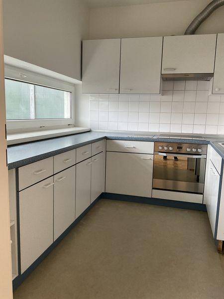 Helle Küche mit weißen Schränken, blauer Arbeitsplatte und integriertem Backofen.