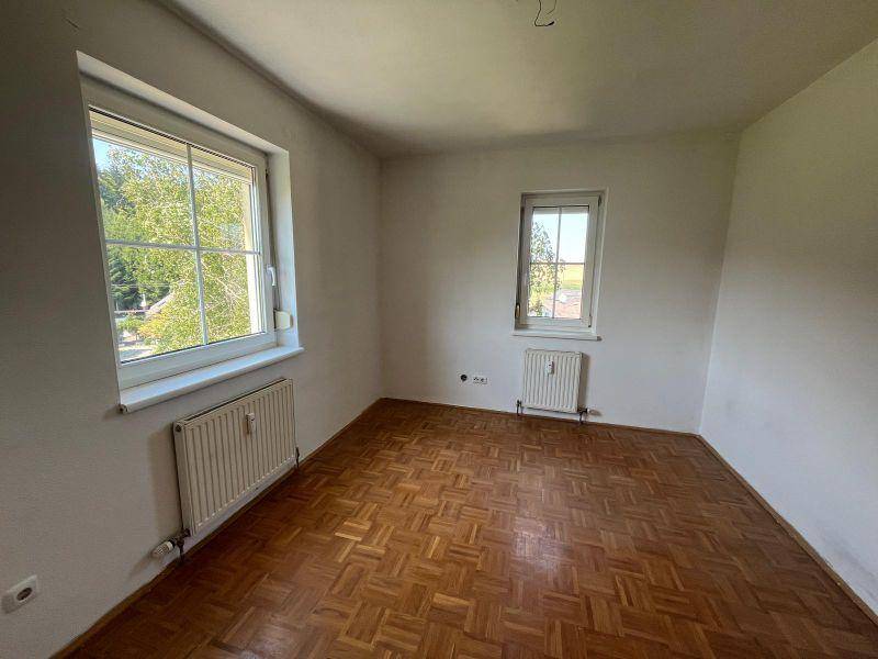 Geräumiges Zimmer mit Parkettboden und zwei Fenstern für viel natürliches Licht.