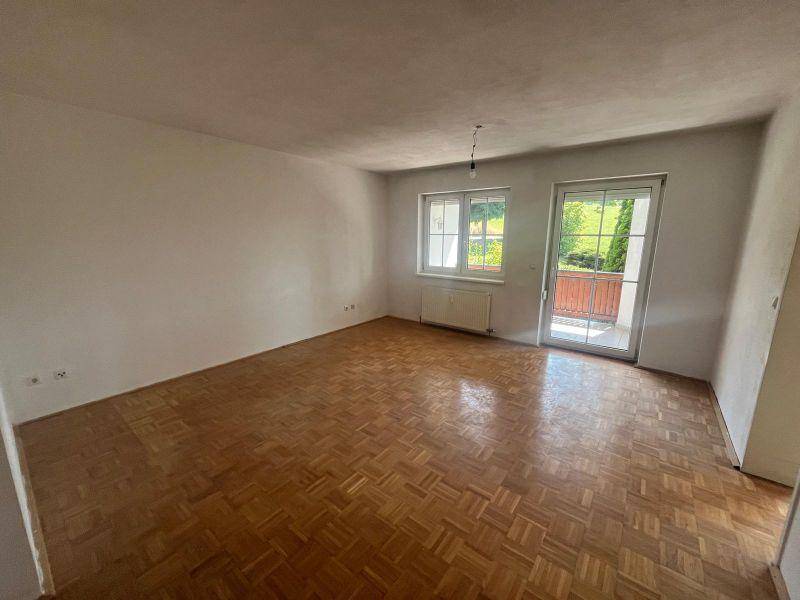Heller Wohnraum mit Parkettboden und direktem Zugang zu einem Balkon.
