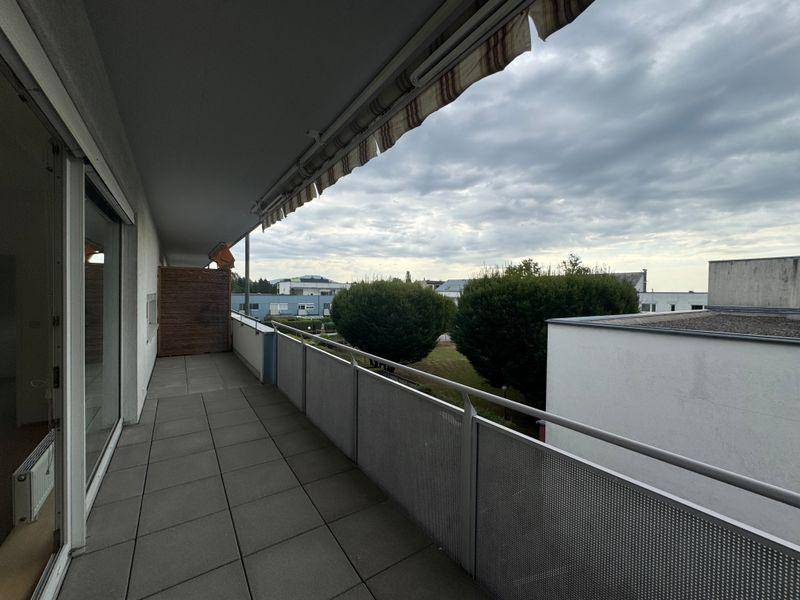 Geräumiger Balkon mit Metallgeländer und Markise, bietet Ausblick auf die Umgebung.