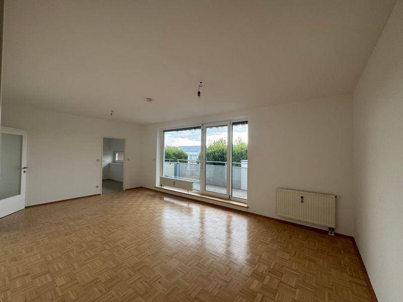 Helles Wohnzimmer mit Parkettboden und breiter Fensterfront, bietet weite Aussicht.
