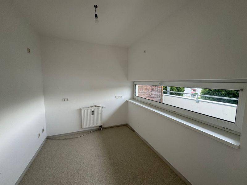 Geräumiges Zimmer mit Heizkörper unter dem breiten Fenster und hellem Bodenbelag.