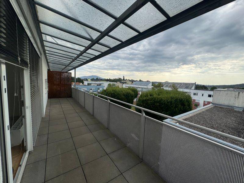 Überdachter Balkon mit Fliesenboden und weitem Blick über die Stadt und die umliegende Landschaft.
