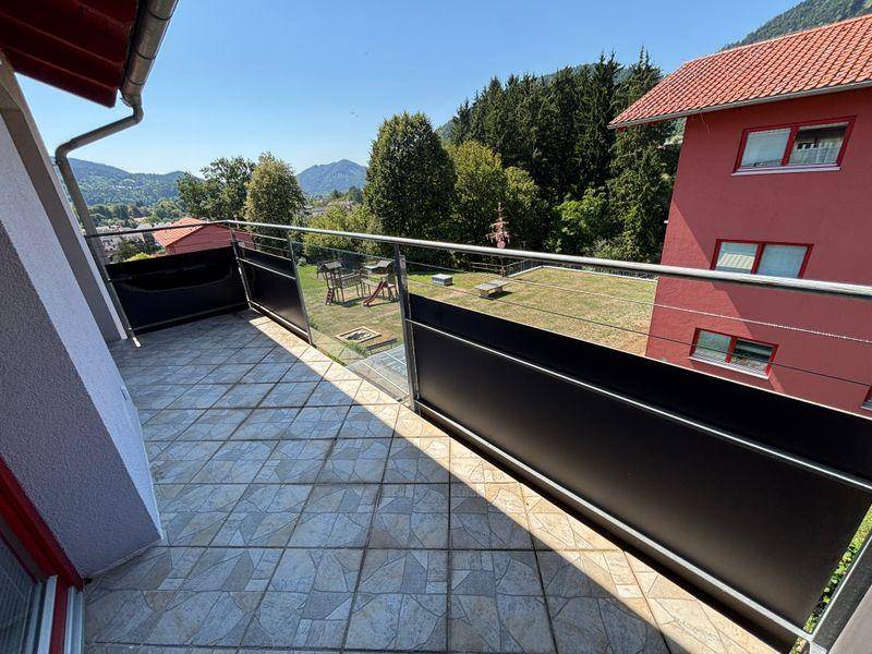 Großer Balkon mit Fliesenboden und Panoramablick auf die umliegende Berglandschaft und Bäume.