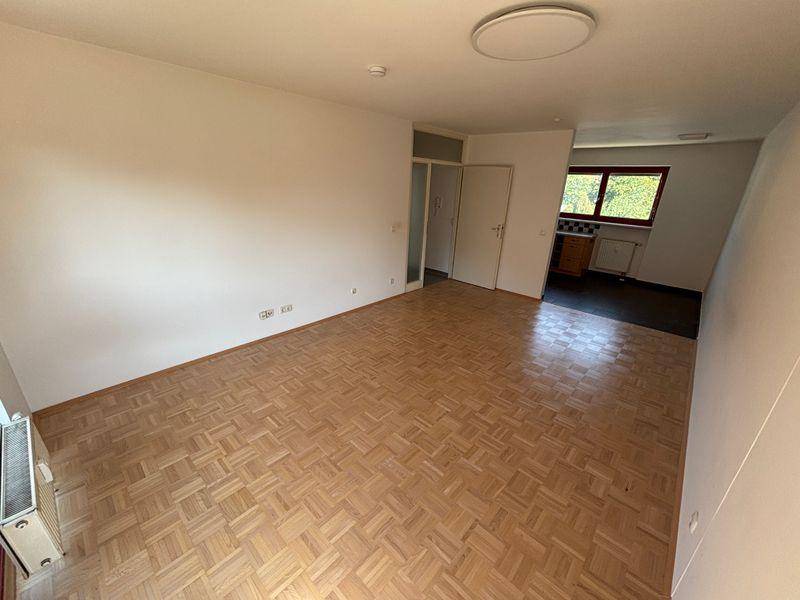 Geräumiger Wohnbereich mit Parkettboden und offener Verbindung zur Küche, ideal für geselliges Beisammensein.