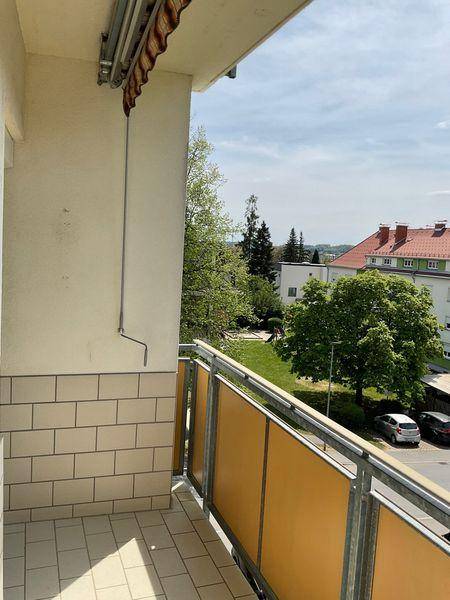 Langer Balkon mit Fliesenboden und Blick auf die Straße sowie die umliegende Wohngegend.