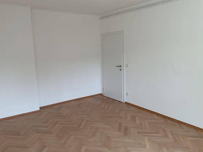 Heller, leerer Raum mit elegantem Fischgrätparkett und einer weißen Innentür.