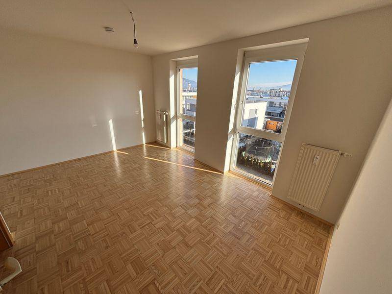 Lichtdurchflutetes Wohnzimmer mit Parkettboden und weitem Ausblick durch große Fenster.