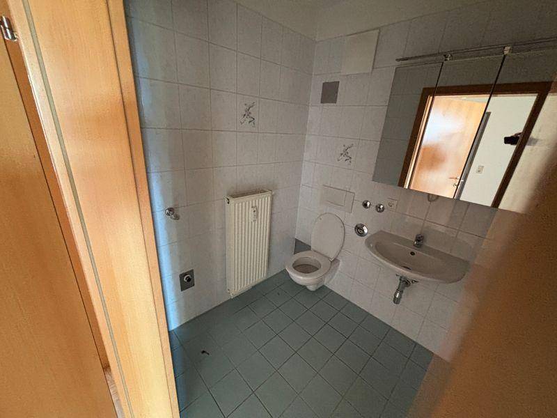 Kleines Badezimmer mit WC, Waschbecken und hellblauen Fliesen, funktional und gepflegt.
