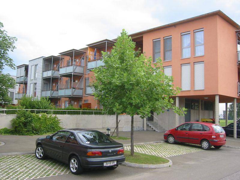 Mehrfamilienhaus mit Außenparkplätzen und begrüntem Umfeld, gut zugänglich.