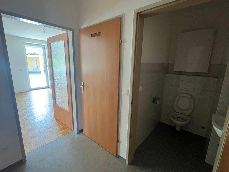 Flur mit Holztür und Zugang zu einem Zimmer sowie einer separaten Gästetoilette.