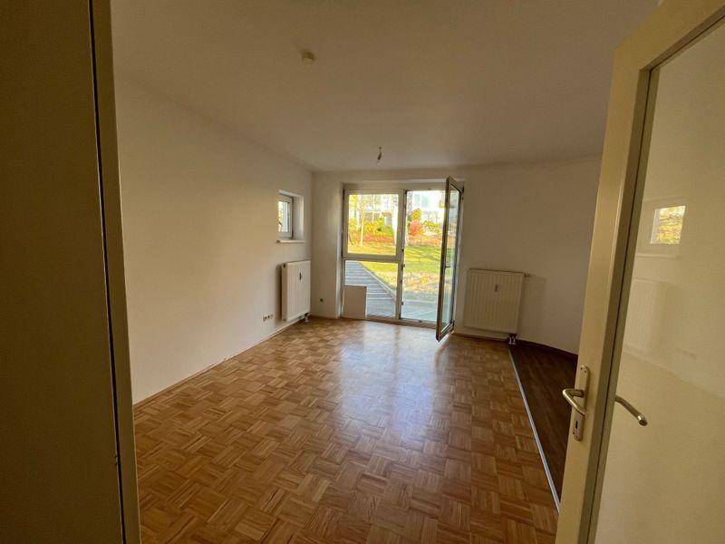 Geräumiger Raum mit Parkettboden und Zugang zum Garten, ideal für helle Wohnbereiche.