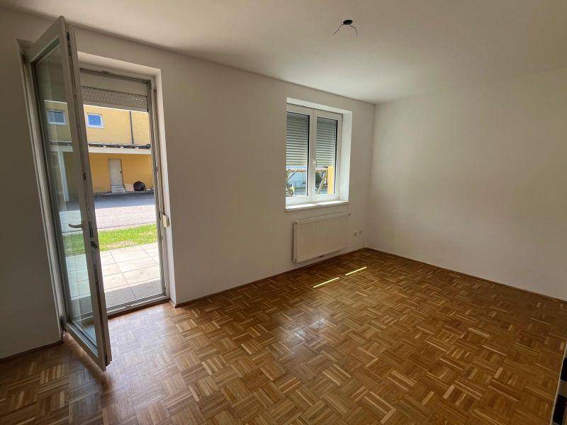 Helles Wohnzimmer mit Parkettboden und großer Glastür, die direkt auf die Terrasse führt.