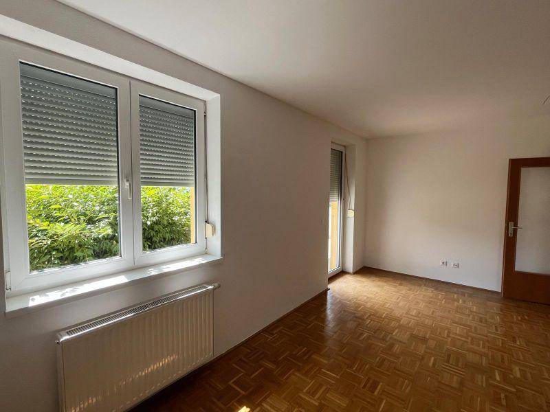 Helles Zimmer mit Parkettboden und großen Fenstern, die einen schönen Blick ins Grüne bieten.