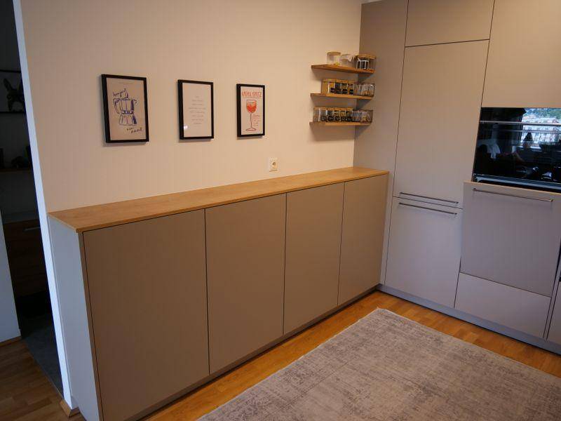 Langer Küchenschrank mit Holzablage und dekorativen Elementen, ergänzt durch moderne Kunst an der Wand.