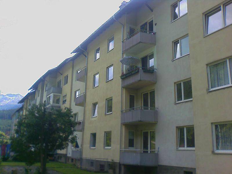 Wohngebäude mit mehreren Balkonen und Blick auf die umliegende Berglandschaft.