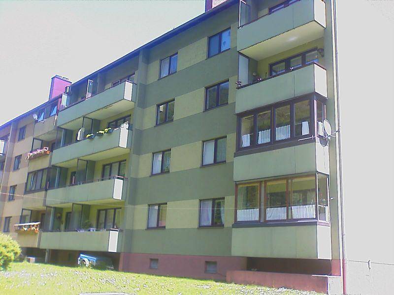 Nahaufnahme der Fassade eines Mehrfamilienhauses mit grünen und beigen Streifen sowie mehreren Balkonen.