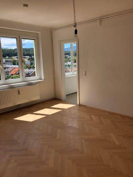 Helles Zimmer mit Fischgrätparkett und Blick auf die Umgebung, ideal als Wohn- oder Schlafzimmer.