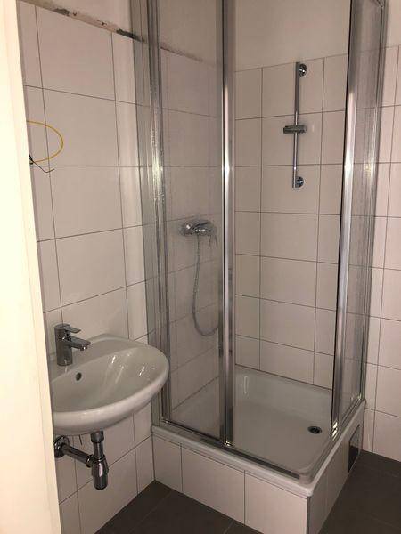 Badezimmer mit Duschkabine und Waschbecken, hell gefliest und funktional eingerichtet.