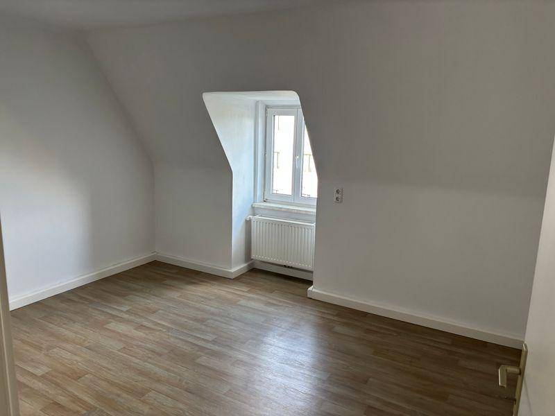 Geräumiges Zimmer mit Dachschräge, Laminatboden und einem Fenster für natürliches Licht.