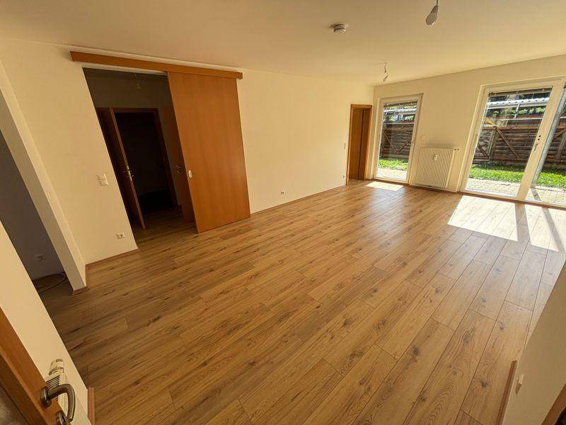 Geräumiges, helles Wohnzimmer mit Laminatboden und großen Fenstern zum Gartenbereich.