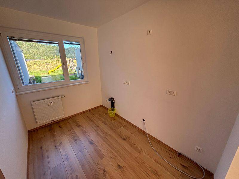 Helles Schlafzimmer mit Laminatboden und Fenster zur Gartenseite, bereit zur Einrichtung.