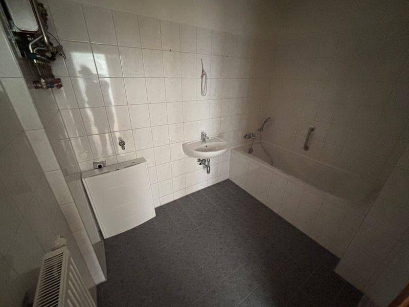 Badezimmer mit Badewanne, Waschbecken und weißen Wandfliesen, funktional und sauber.