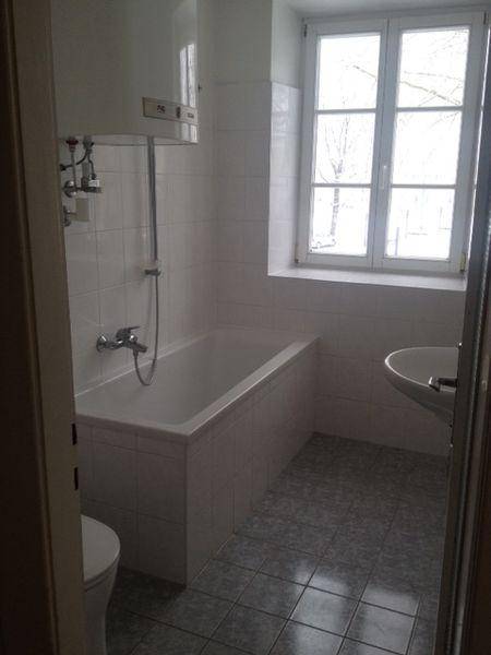 Badezimmer mit Badewanne, Waschbecken, Toilette und einem Fenster für Tageslicht.