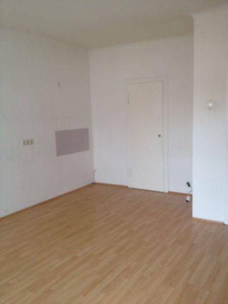 Leerer Raum mit hellem Laminatboden und weißen Wänden, bereit zur Einrichtung.