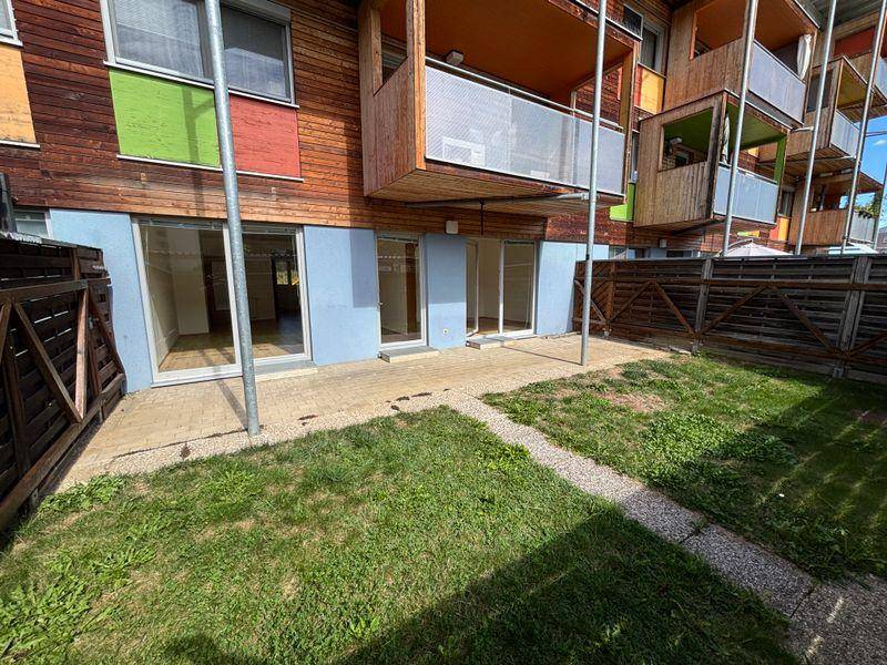 Sonniger Terrassenbereich mit Rasenfläche und direktem Zugang zu den Innenräumen des Gebäudes.