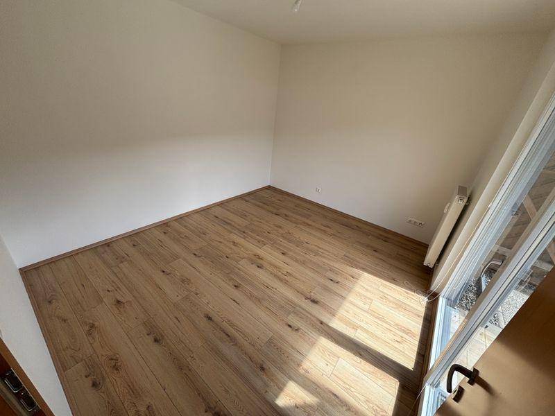 Helles Zimmer mit Laminatboden und Zugang zu einem privaten Außenbereich.