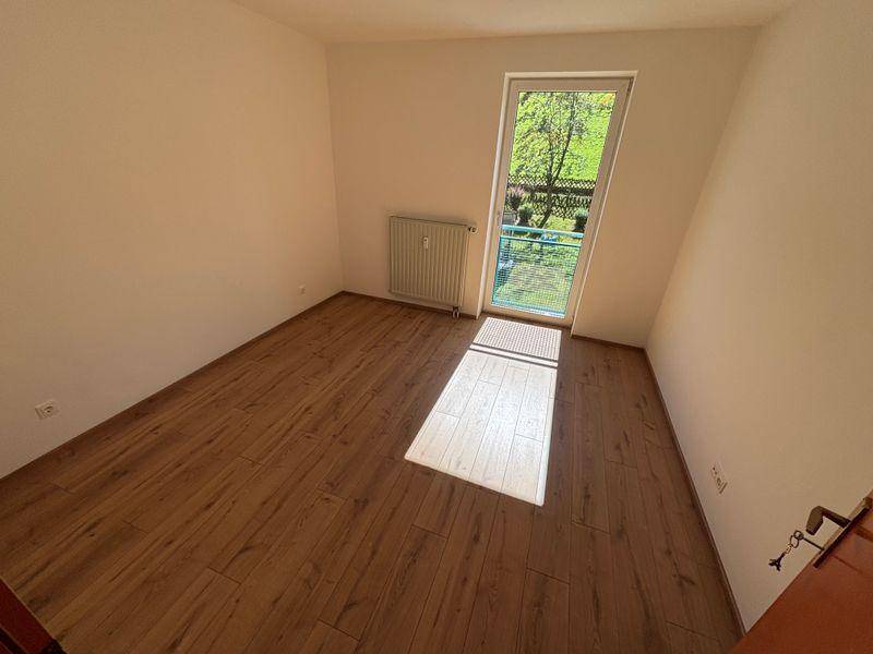 Helles Zimmer mit Laminatboden und Zugang zum Balkon durch eine Glastür.