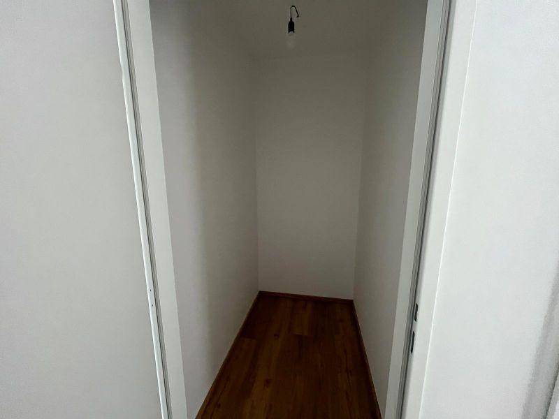 Kleiner, leerer Abstellraum mit Holzboden und einfacher Beleuchtung.