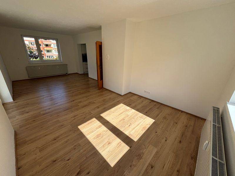 Heller Wohnraum mit Laminatboden und Blick auf die städtische Umgebung durch das Fenster.