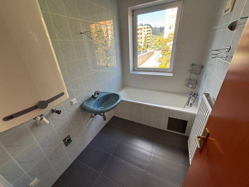 Badezimmer mit Badewanne, Waschbecken und hellblauen Fliesen an den Wänden.