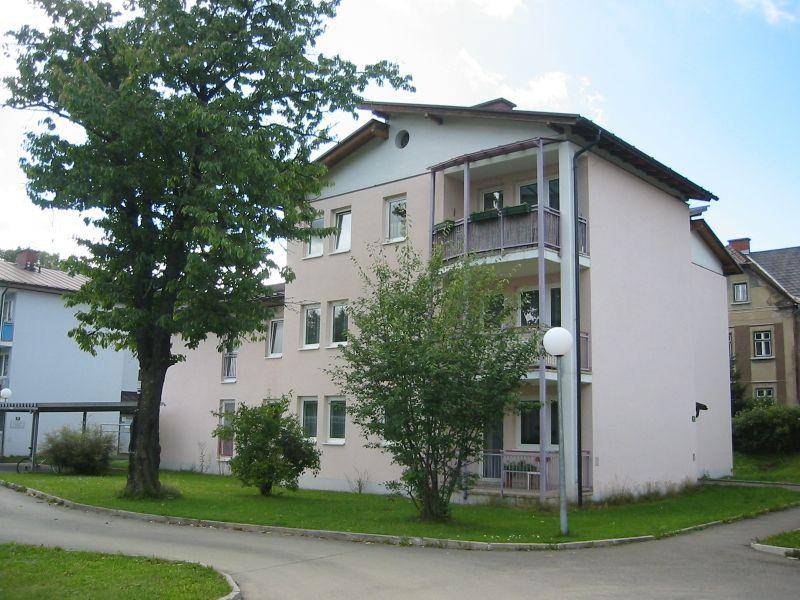 Wohngebäude mit gepflegter Fassade, umgeben von Grünflächen und Bäumen.