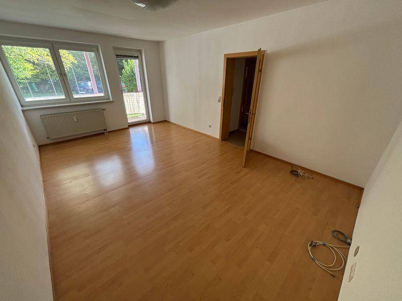 Helles Wohnzimmer mit Laminatboden und Zugang zum Balkon.