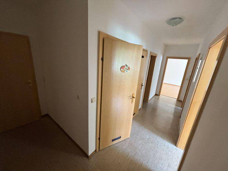 Heller Flur mit mehreren Holztüren und PVC-Bodenbelag.