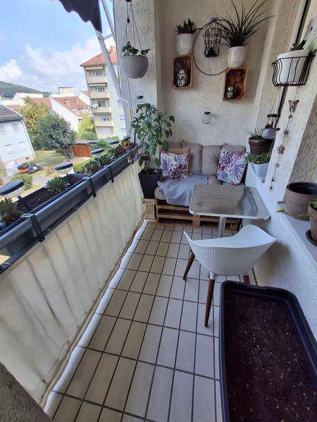 Möblierter Balkon mit Fliesenboden, Pflanzen und Blick auf die Umgebung.