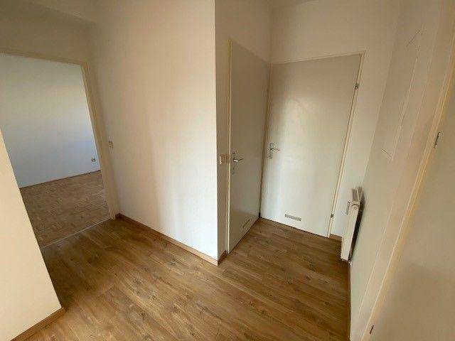 Heller Flur mit Laminatboden und Zugang zu weiteren Räumen.