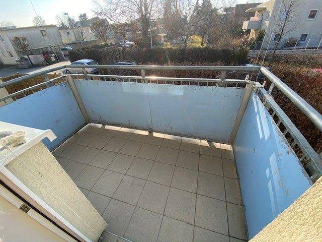 Kleiner Balkon mit Fliesenboden und Metallgeländer, Blick auf die Umgebung.