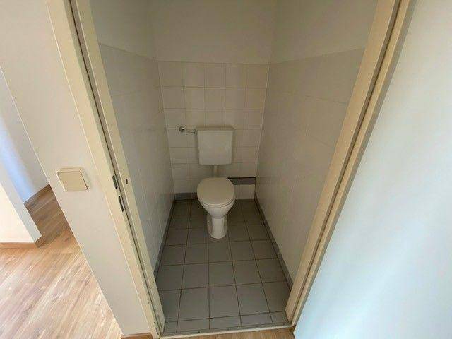 Separate Toilette mit Fliesenboden und weißer Keramik.