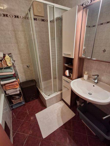Badezimmer mit Duschkabine, Waschbecken und Spiegelschrank in warmen Farbtönen.